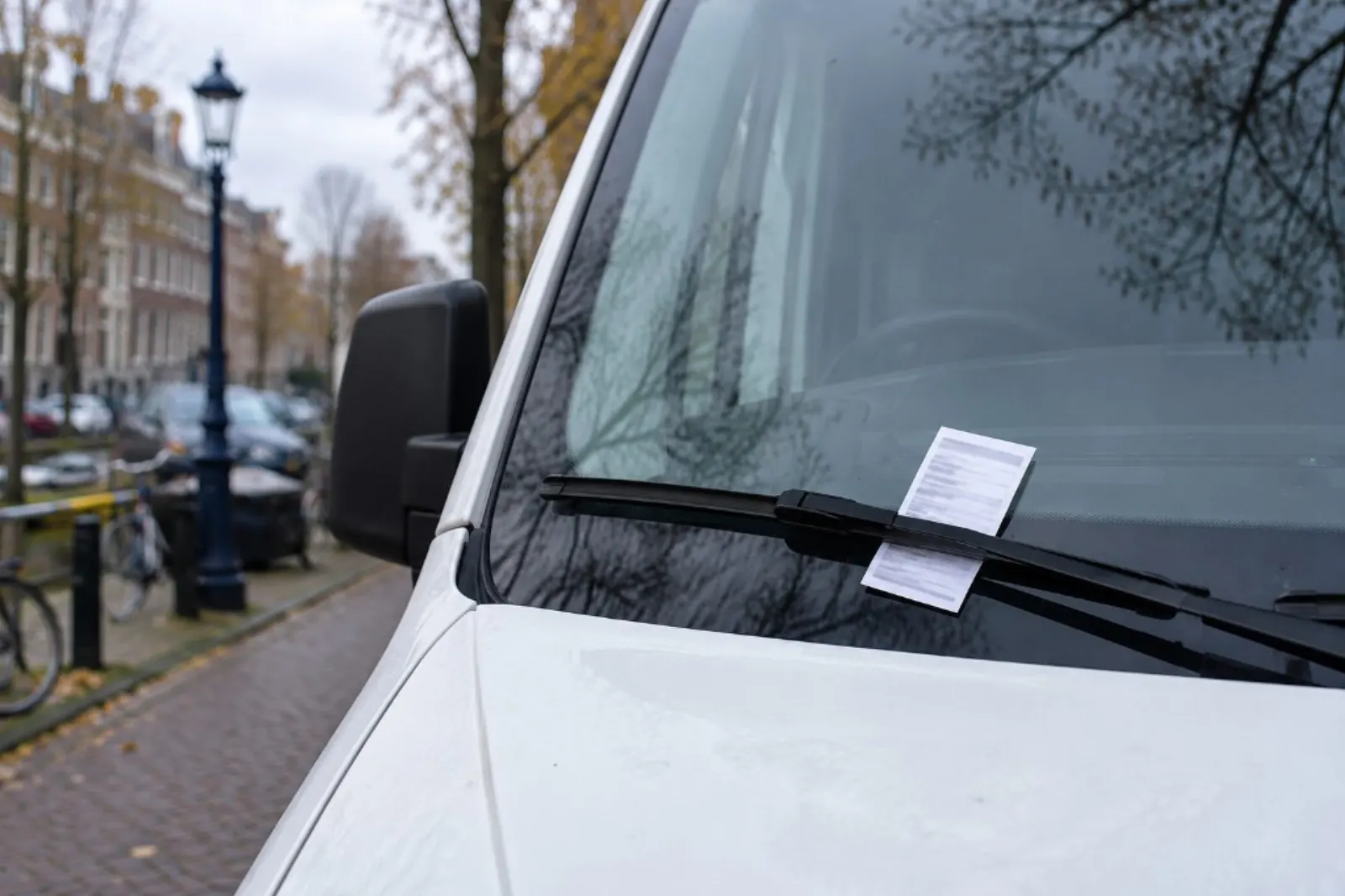 Parkeerbon onder de ruitenwisser van een bestelbus bij een gracht
